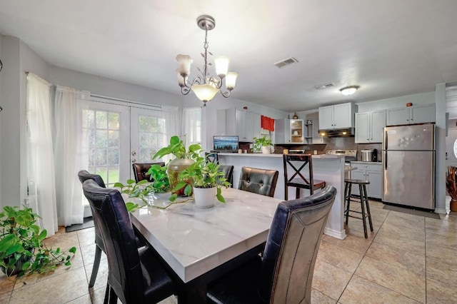 dining area featuring light tile patterned floors, visible vents, a notable chandelier, and french doors