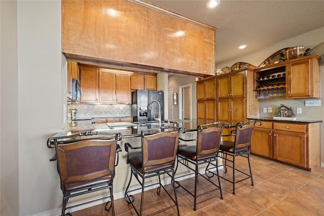 130 Sobrante Rd Unit 309, Belton, TX 76513 - kitchen with black fridge with ice dispenser, brown cabinetry, decorative backsplash, a peninsula, and a breakfast bar