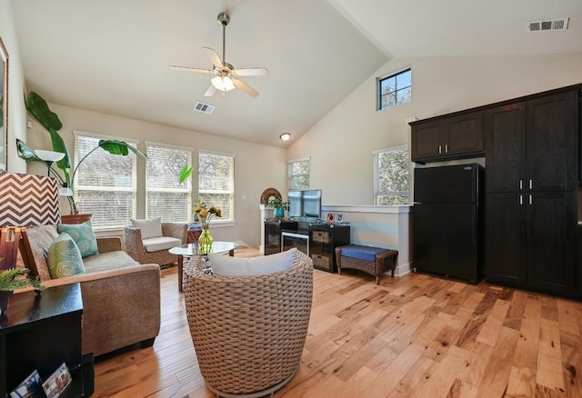 living area with ceiling fan, high vaulted ceiling, visible vents, and light wood-style floors