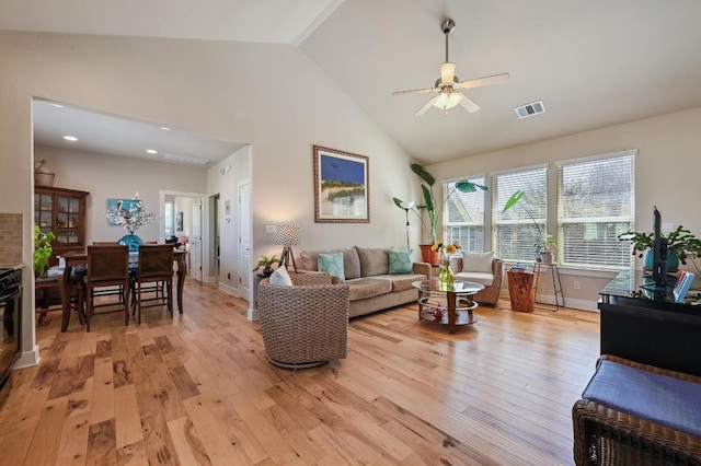 living room with high vaulted ceiling, visible vents, ceiling fan, and light wood finished floors