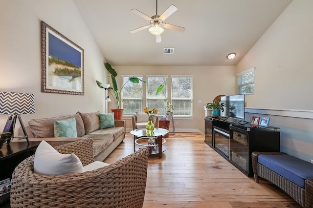 living area featuring lofted ceiling, a healthy amount of sunlight, light wood-style flooring, and visible vents