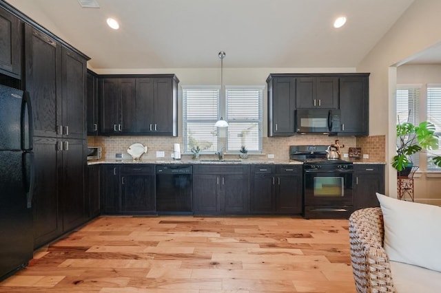 kitchen featuring light stone counters, lofted ceiling, light wood-style floors, and black appliances