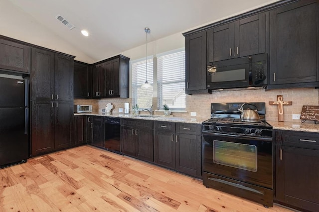 kitchen with lofted ceiling, visible vents, black appliances, and light stone countertops