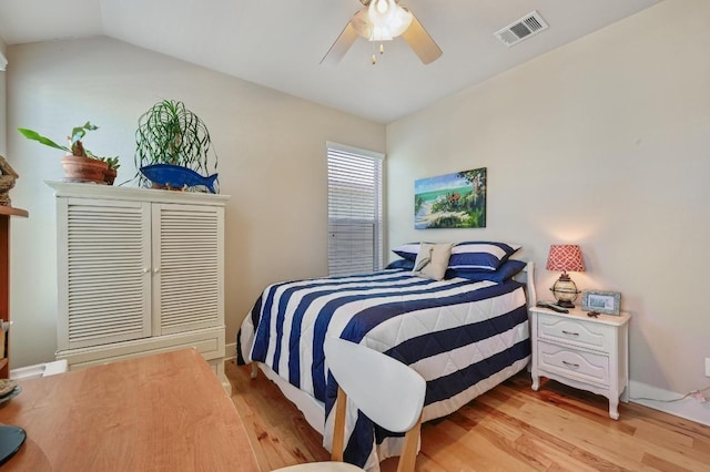 bedroom with lofted ceiling, light wood-style flooring, visible vents, baseboards, and a ceiling fan