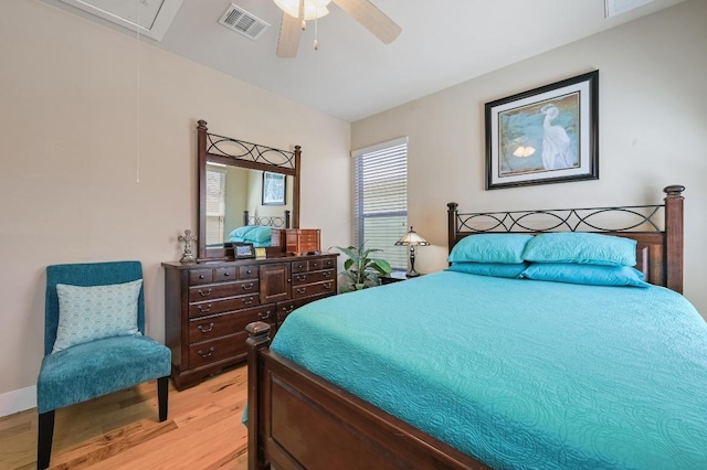 bedroom with light wood finished floors, attic access, visible vents, and ceiling fan