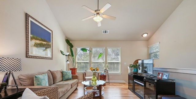 living area featuring lofted ceiling, visible vents, ceiling fan, light wood-type flooring, and baseboards