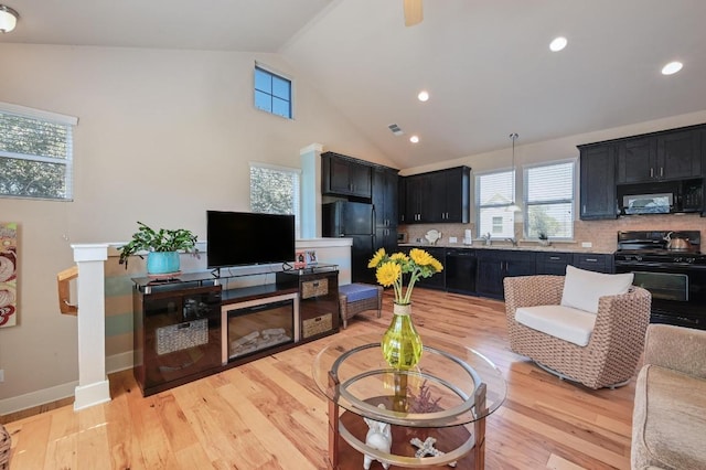 living area featuring high vaulted ceiling, light wood-style flooring, recessed lighting, visible vents, and baseboards