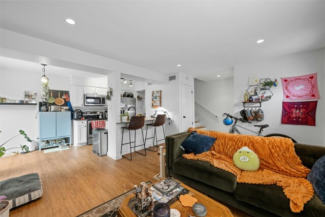 living area featuring light wood-style floors, stairs, visible vents, and recessed lighting