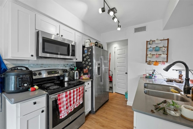 kitchen with light wood-style flooring, a sink, visible vents, appliances with stainless steel finishes, and backsplash