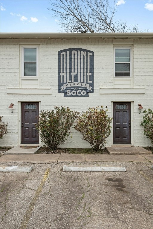 view of front facade with uncovered parking and brick siding