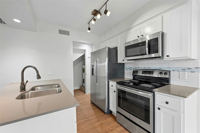 kitchen featuring appliances with stainless steel finishes, visible vents, a sink, and tasteful backsplash