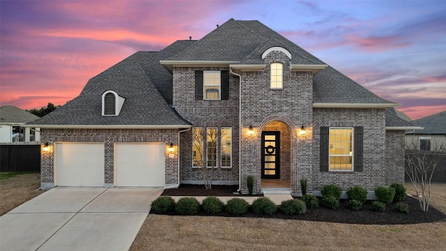 french provincial home with driveway, roof with shingles, an attached garage, and fence