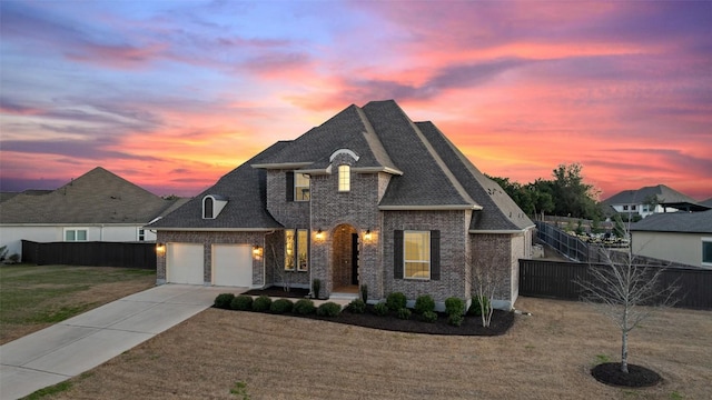 french provincial home featuring an attached garage, fence, concrete driveway, roof with shingles, and a front yard