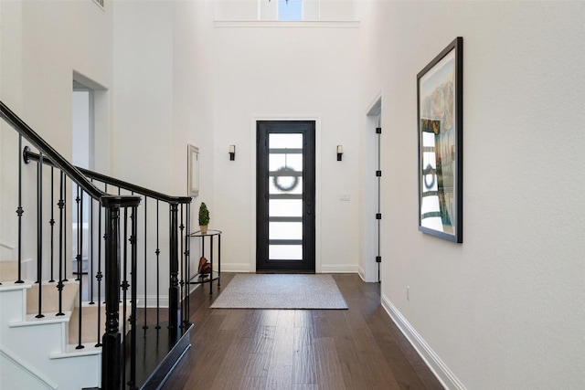 entryway featuring dark wood-style floors, a high ceiling, stairway, and baseboards