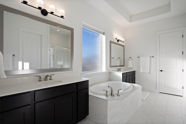 bathroom featuring a tray ceiling, a garden tub, two vanities, a sink, and a shower stall