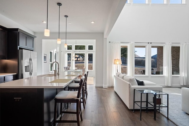 kitchen featuring stainless steel fridge with ice dispenser, a breakfast bar, open floor plan, dark wood-type flooring, and light countertops