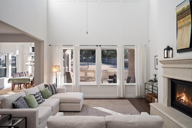 living area featuring a high ceiling, dark wood finished floors, and a glass covered fireplace