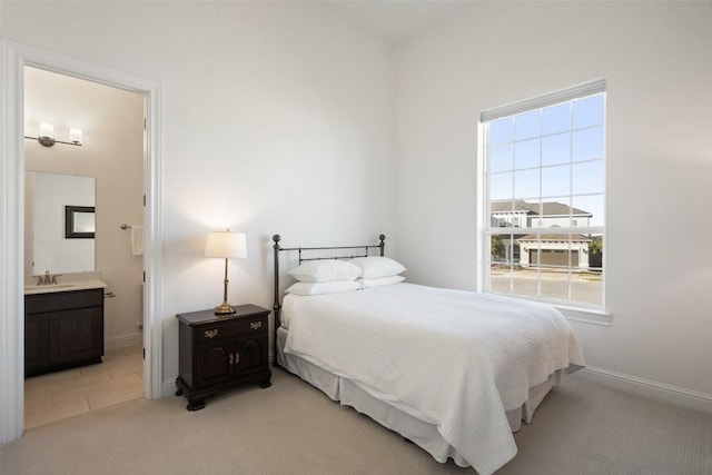 bedroom with ensuite bath, baseboards, a sink, and light colored carpet