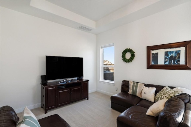 living area featuring a raised ceiling, light carpet, visible vents, and baseboards