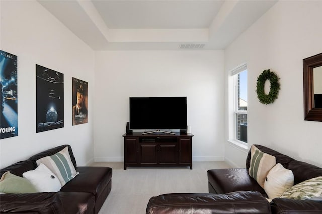 living room with light carpet, a tray ceiling, visible vents, and baseboards