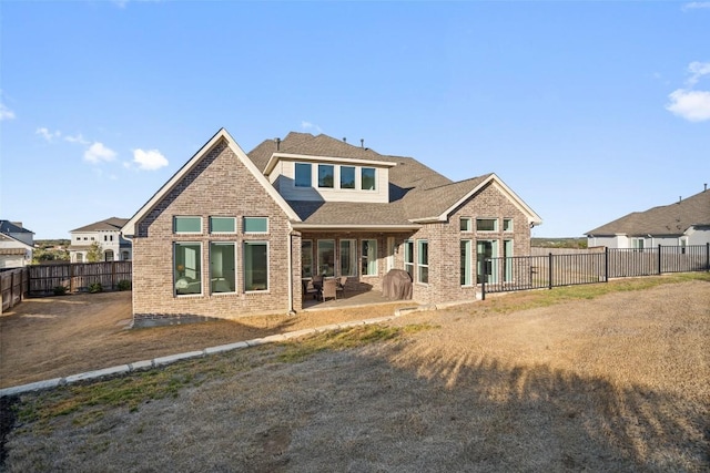 rear view of property with brick siding, a patio area, and a fenced backyard