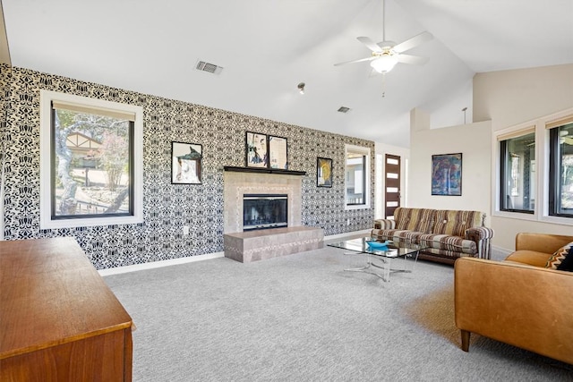 carpeted living room with visible vents, high vaulted ceiling, a tile fireplace, baseboards, and wallpapered walls