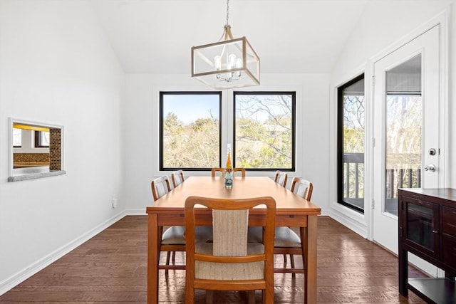 dining room with dark wood finished floors, a notable chandelier, vaulted ceiling, and baseboards