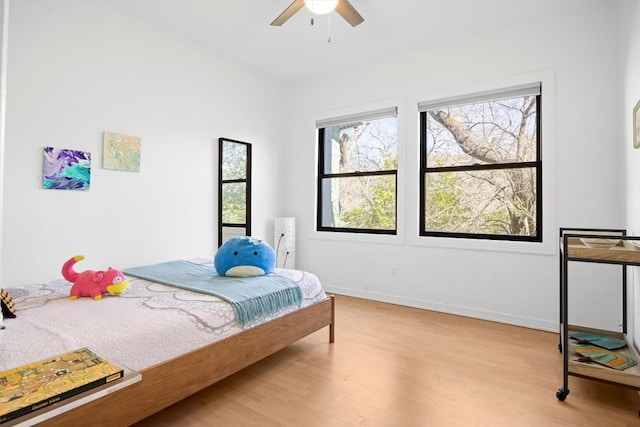 bedroom with a ceiling fan, baseboards, and wood finished floors