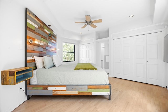 bedroom featuring ceiling fan, recessed lighting, wood finished floors, and multiple closets