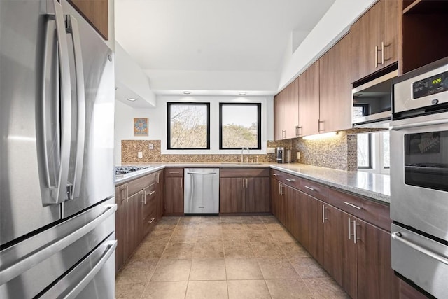 kitchen featuring a warming drawer, stainless steel appliances, backsplash, and a sink