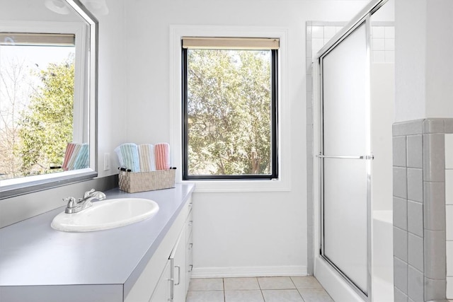 bathroom with a shower with door, vanity, baseboards, and tile patterned floors