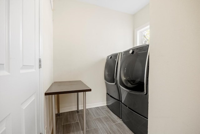 laundry area with wood finish floors, laundry area, baseboards, and washing machine and clothes dryer