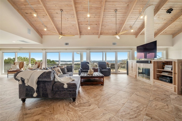 living area featuring beam ceiling, rail lighting, a glass covered fireplace, high vaulted ceiling, and wooden ceiling