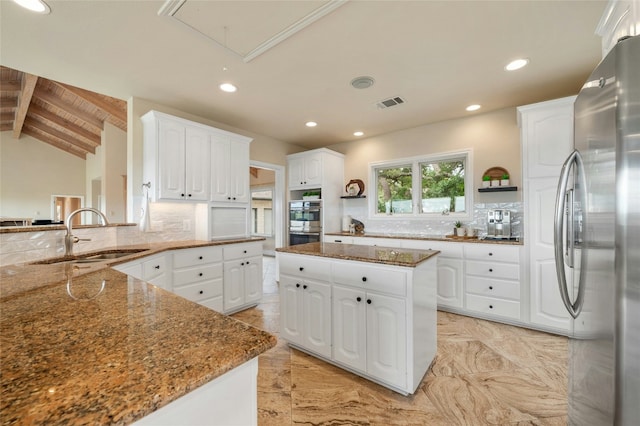 kitchen featuring stainless steel appliances, visible vents, backsplash, a sink, and dark stone counters