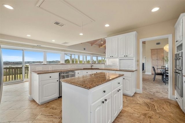 kitchen featuring tasteful backsplash, visible vents, appliances with stainless steel finishes, a center island, and a peninsula