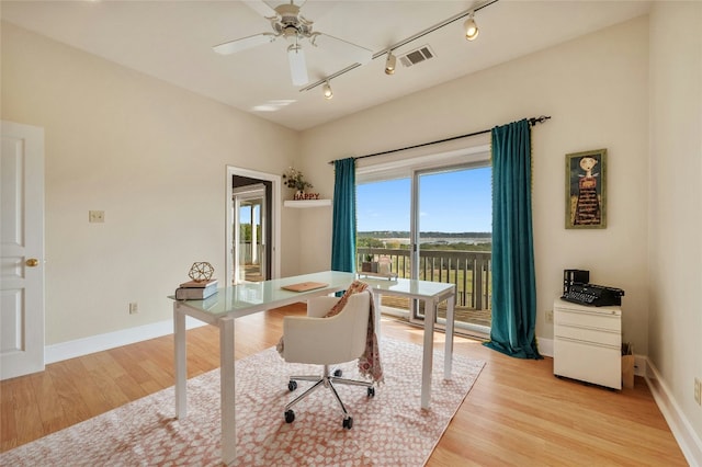 office featuring light wood-style flooring, a ceiling fan, visible vents, and baseboards