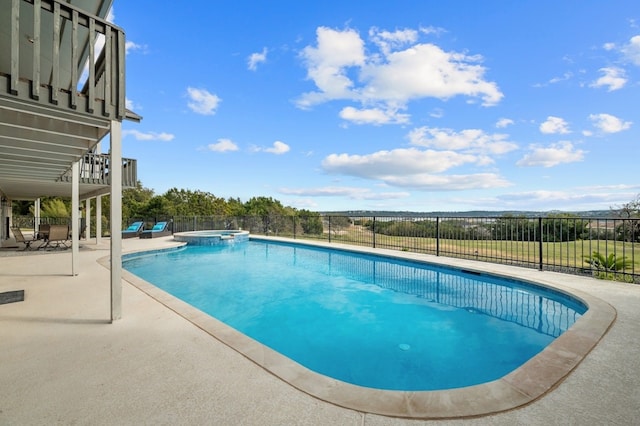 view of swimming pool featuring a pool with connected hot tub, fence, and a patio