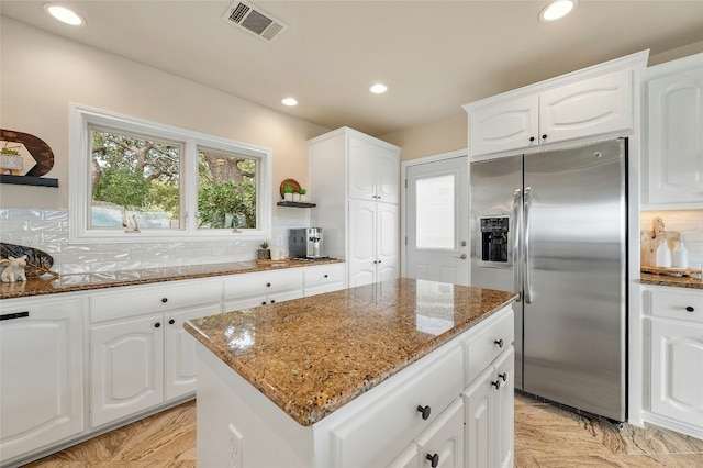 kitchen featuring tasteful backsplash, visible vents, dark stone counters, and stainless steel fridge with ice dispenser