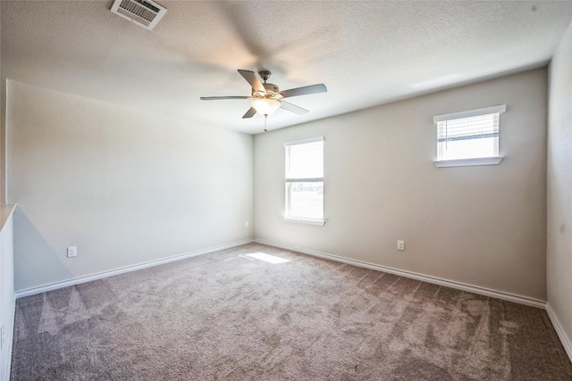 spare room featuring ceiling fan, a wealth of natural light, carpet flooring, and visible vents