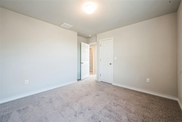 spare room with light carpet, visible vents, and baseboards