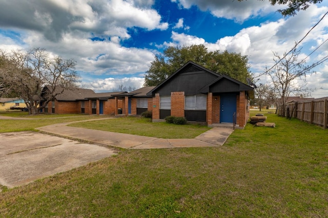 view of front of house featuring brick siding, a front yard, and fence