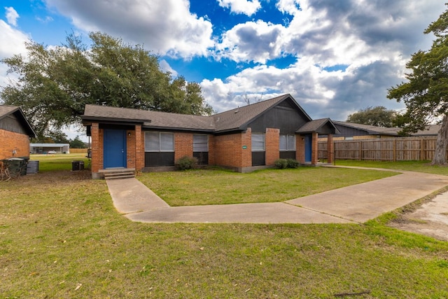 view of front of home with brick siding, a front lawn, and fence