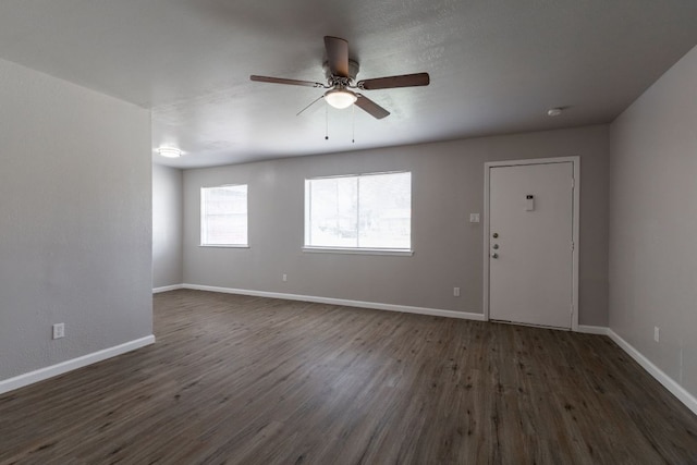 interior space featuring a ceiling fan, baseboards, and dark wood-type flooring