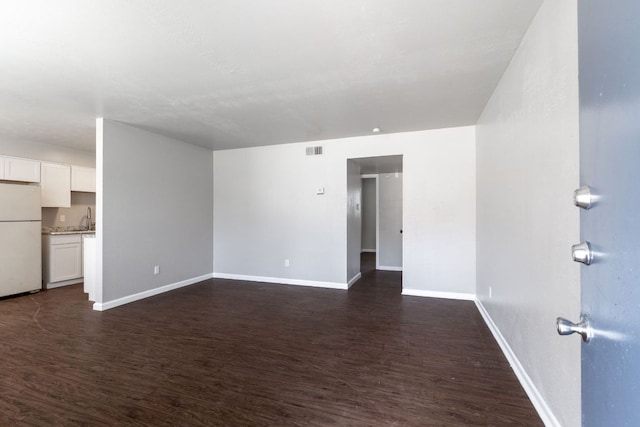 spare room with visible vents, dark wood finished floors, a sink, and baseboards