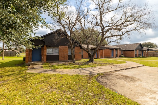 view of front facade featuring concrete driveway, brick siding, and a front yard