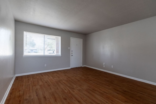 spare room featuring baseboards and wood finished floors