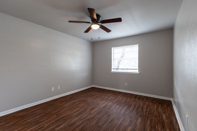 unfurnished room with dark wood-type flooring, a ceiling fan, and baseboards