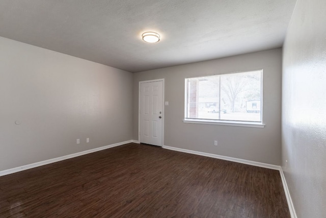 empty room featuring dark wood-style floors and baseboards