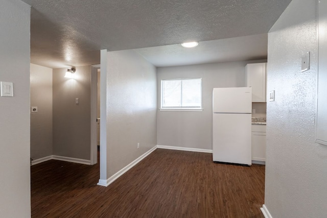 spare room with a textured ceiling, dark wood finished floors, and baseboards