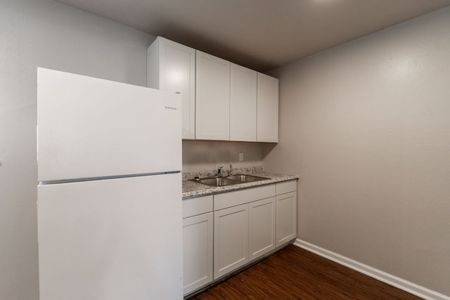 kitchen with a sink, baseboards, light countertops, freestanding refrigerator, and dark wood finished floors